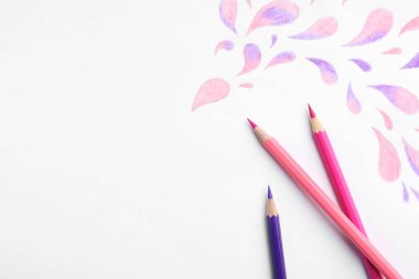 Beyaz arkaplanda soyut çizimler ve renkli kalemler, üst görünüm