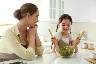 Anne ve kızı mutfakta salata pişiriyor.