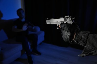 Adam kurbanını karanlık odada silahla hedef alıyor, yakın plan. Tehlikeli suçlu.