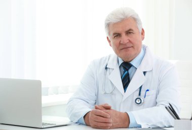 İş yerinde beyaz önlüklü kıdemli doktorun portresi.