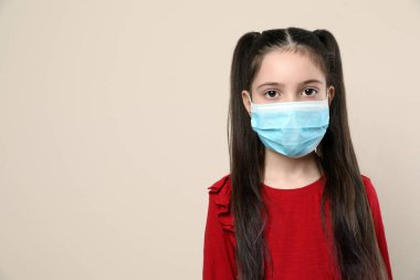 Bej arka planda tıbbi maskeli küçük bir kız, mesaj için yer var. Virüs koruması