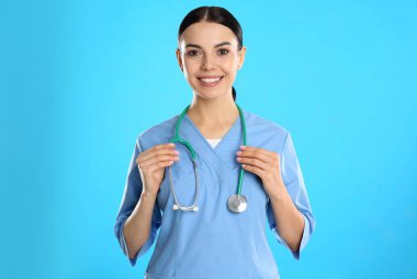 Mavi arka planda steteskobu olan genç doktorun portresi.