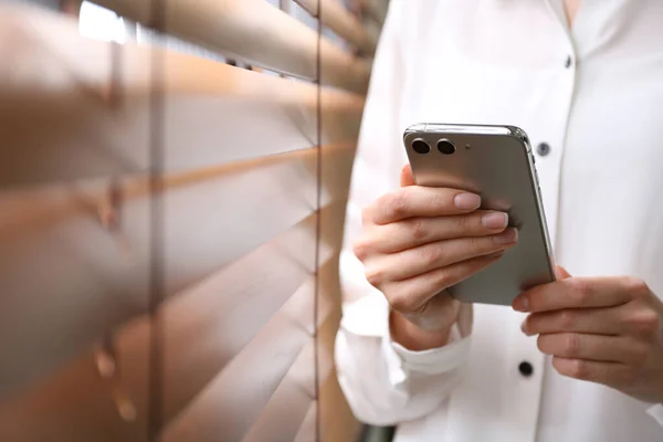 Mujer Joven Usando Teléfono Inteligente Moderno Cerca Ventana Interior Primer — Foto de Stock