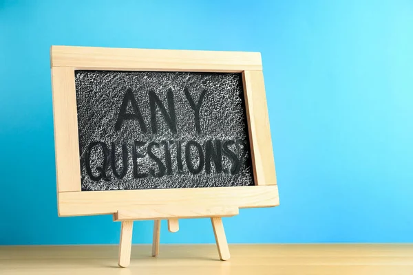 Blackboardフレーズ青の背景に木製のテーブルに関する質問 — ストック写真