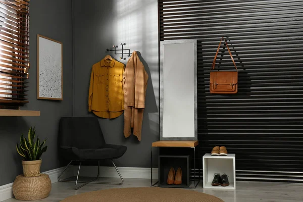 Hallway interior with modern furniture, mirror and hanging clothes