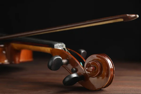 Classic violin and bow on wooden background, closeup