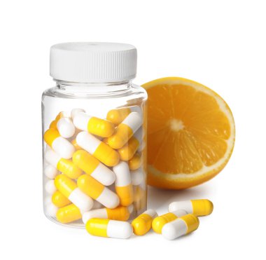 Beyaz arka planda vitamin hapları ve limon şişesi.