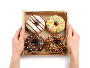 Beyaz arka planda nefis jöleli çöreklerle dolu bir kutu tutan kadın.