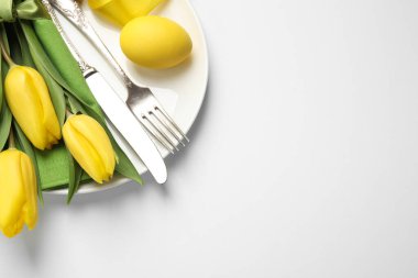 Beyaz arkaplanda çiçek dekoru olan bayramlık Paskalya sofrası.