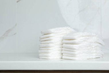 Banyodaki tezgahta bebek bezi yığını var.