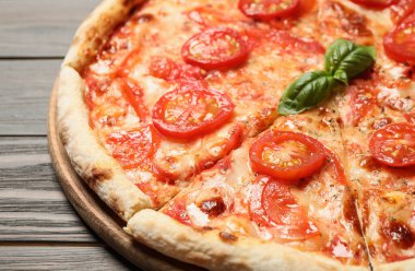 Lezzetli pizza Margherita ahşap masada, yakın çekim manzaralı.