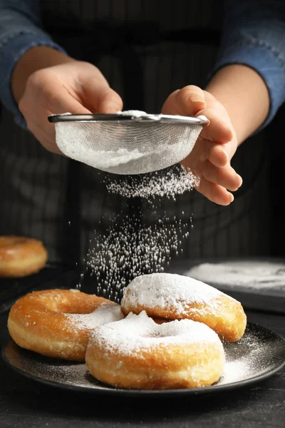 Vrouw Versiert Heerlijke Donuts Met Poedersuiker Aan Zwarte Tafel Close — Stockfoto