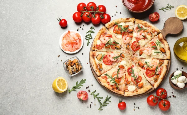 淡灰色桌子上的美味海鲜披萨和新鲜配料 — 图库照片