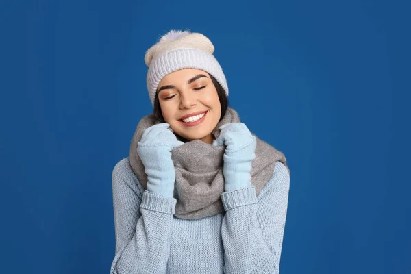 暖かいセーター スカーフ 帽子を青い背景に身に着けている若い女性 冬の季節 — ストック写真