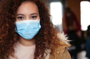 Evin içinde tek kullanımlık maskeli Afro-Amerikalı bir kadın. Virüs koruması