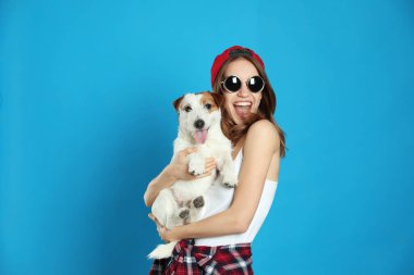 Açık mavi arka planda sevimli Jack Russell Terrier 'ı olan genç bir kadın. Sevimli hayvan