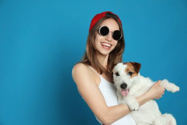 Açık mavi arka planda Jack Russell Terrier 'ı olan genç bir kadın. Mesaj için yer var. Sevimli hayvan
