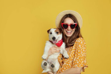 Sarı arka planda sevimli Jack Russell Terrier 'ı olan genç bir kadın. Sevimli hayvan