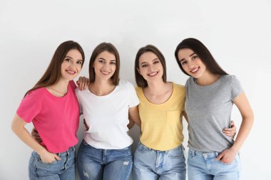 Kot pantolonlu güzel genç bayanlar ve beyaz arka planda renkli tişörtler. Kadın Günü