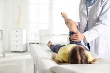 Klinikte küçük bir hastanın bacağını muayene eden profesyonel ortopedist.