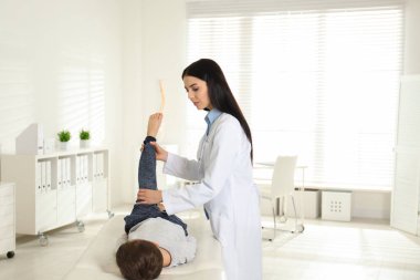 Klinikte küçük bir hastanın bacağını muayene eden profesyonel ortopedist.