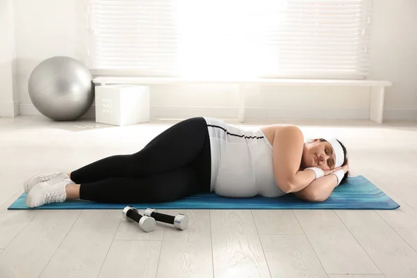 懒惰的超重女人在健身房睡觉而不是在垫子上训练 — 图库照片