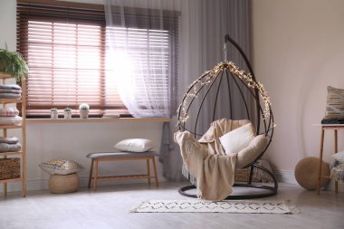 Modern oturma odasında peri ışıkları olan rahat bir sallanan sandalye. İç tasarım