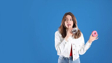 Mavi arka planda donutları olan güzel genç bir kadın.