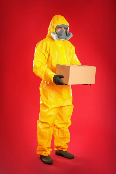 Mann Chemikalienschutzanzug Mit Pappschachtel Auf Rotem Hintergrund Verhinderung Der Ausbreitung — Stockfoto