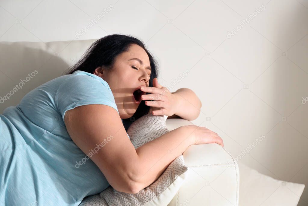 Lazy overweight woman resting on sofa at home
