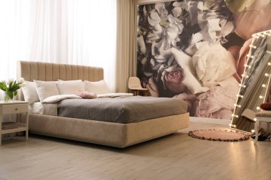 Büyük yataklı, aynalı ve çiçek desenli güzel bir oda.