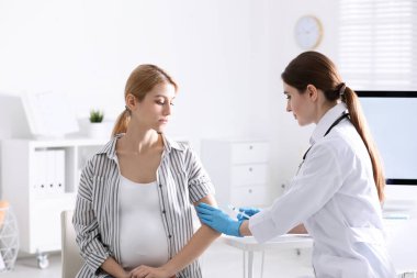 Hastanede hamile bir kadına iğne yapan bir doktor. Aşılama kavramı