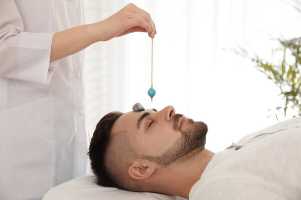 Молодой человек во время сеанса кристального исцеления в кабинете терапии