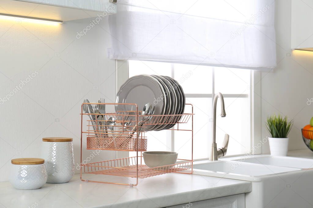 Clean dishes on drying rack in modern kitchen interior
