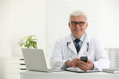 Ofiste akıllı telefonu olan kıdemli doktor.