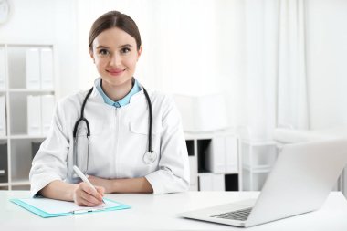 İş yerinde beyaz önlüklü genç kadın doktor portresi