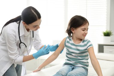 Modern klinikte küçük bir çocuğu aşılayan doktor.