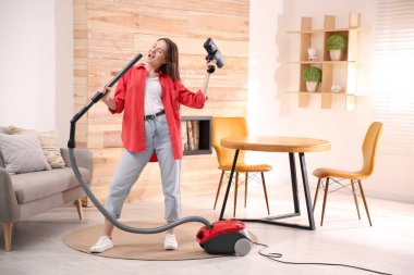 Evini süpürürken eğlenen genç kadın.