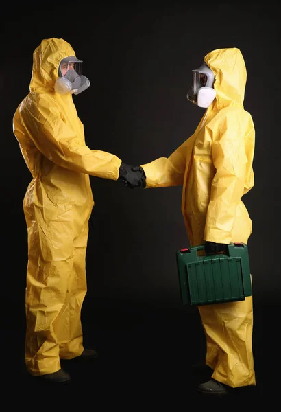 Άνδρας Και Γυναίκα Στολές Χημικής Προστασίας Κάνουν Χειραψία Μαύρο Φόντο — Φωτογραφία Αρχείου