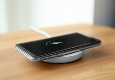Odadaki kablosuz yayında akıllı telefon şarj ediliyor.