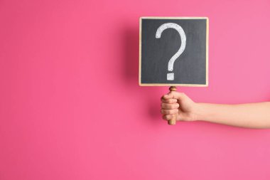 Woman holding blackboard with question mark on pink background, closeup. Space for text clipart