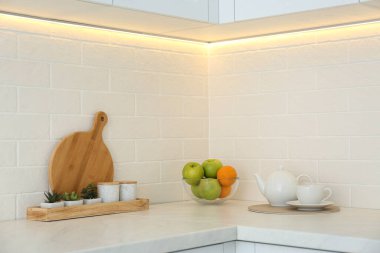 Modern mutfağın tezgahında taze meyve ve çaydanlık.