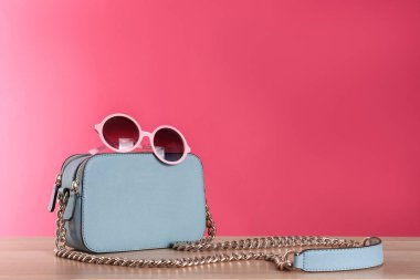 Ahşap masada şık bir kadın çantası ve güneş gözlüğü. Metin için boşluk