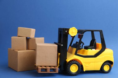Forklift modeli ve mavi arka planda karton kutular. Kurye servisi