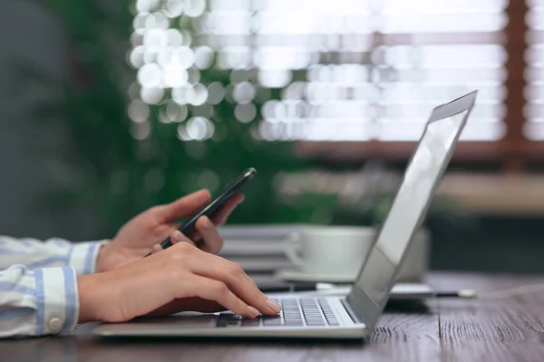 Kvinna Med Mobiltelefon Arbetar Modern Bärbar Dator Vid Bordet Närbild — Stockfoto