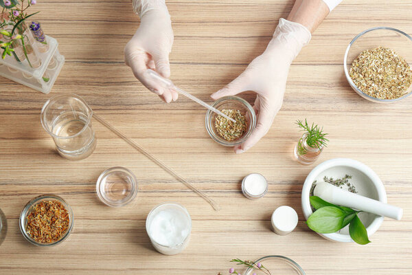 Scientist developing cosmetic product at wooden table in laboratory, top view