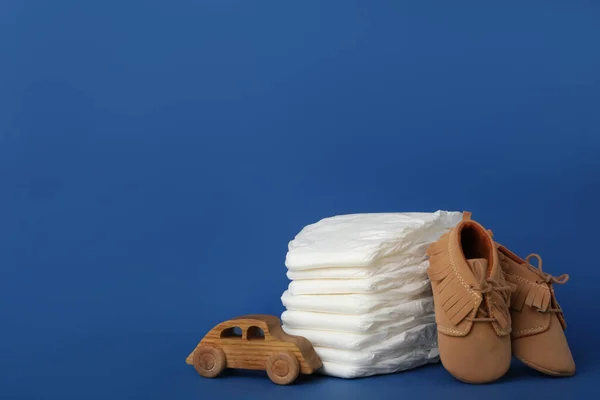 Diapers, baby accessories and toy car on blue background. Space for text