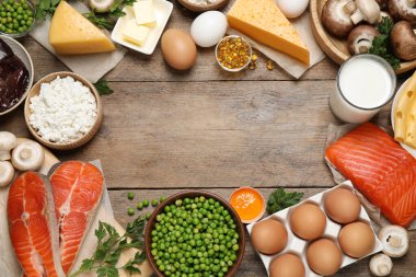 Tahta masanın üzerinde D vitamini açısından zengin ürünlerle bezenmiş düz bir kompozisyon. Metin için boşluk