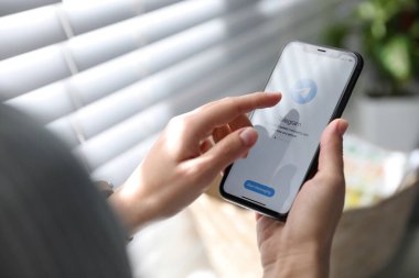 MYKOLAIV, UKRAINE - 16 Mart 2020: Kapalı alanda Telegram uygulamalı iPhone 11 'i tutan kadın, yakın plan