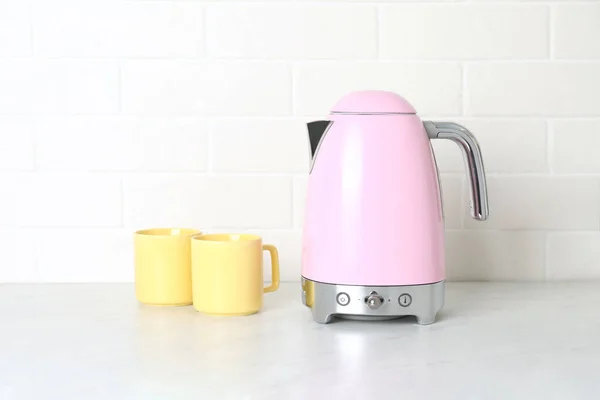 厨房柜台上的现代电水壶和杯子 — 图库照片